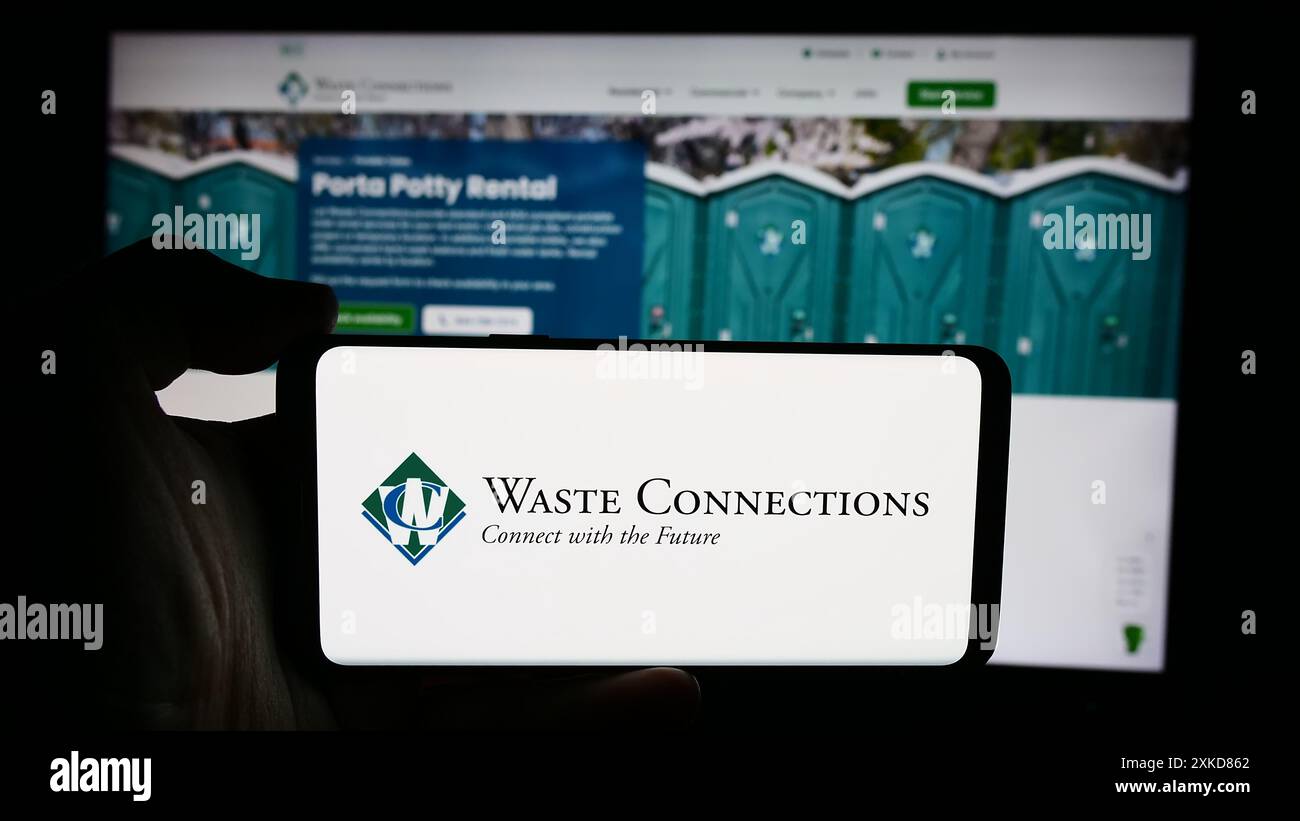 Persona che detiene un cellulare con il logo della società di riciclaggio statunitense Waste Connections Inc. Di fronte alla pagina Web aziendale. Mettere a fuoco il display del telefono. Foto Stock