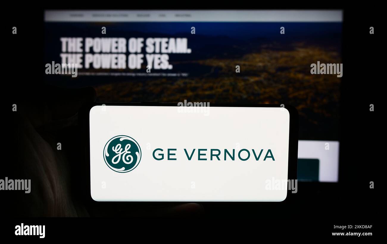 Persona che detiene un cellulare con il logo della società statunitense di apparecchiature energetiche GE Vernova Inc. Di fronte alla pagina Web aziendale. Mettere a fuoco il display del telefono. Foto Stock