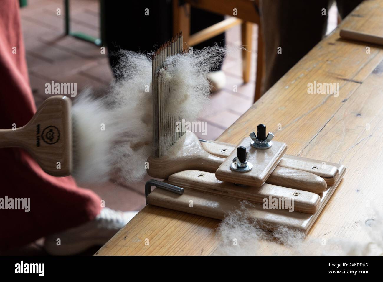 La lana di pecora è preparata per la filatura tradizionale presso una stazione di pettinatura. Foto Stock