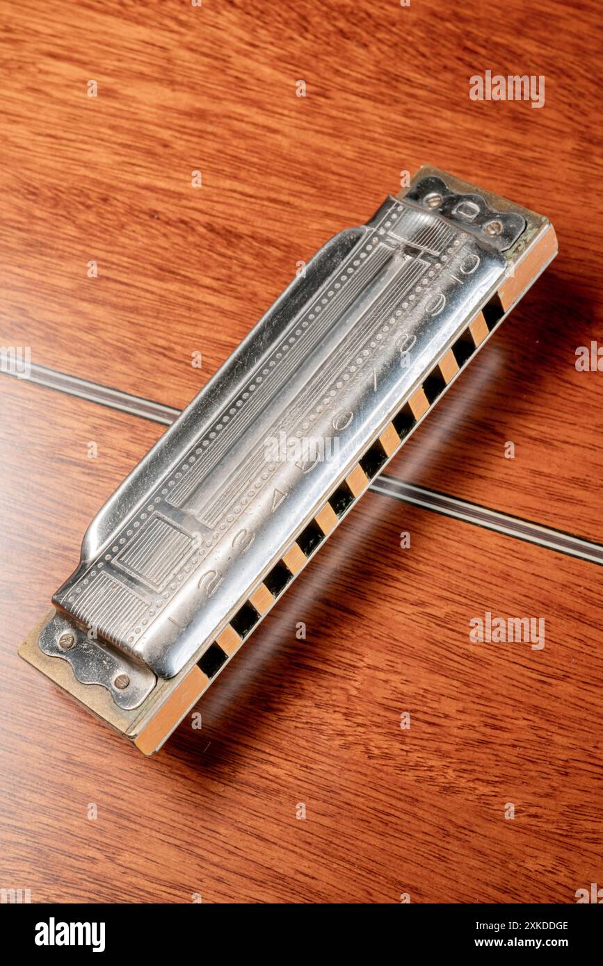 L'armonica diatonica a 10 buche d'epoca è appoggiata sul retro di una chitarra acustica rovesciata: Phillip Roberts Foto Stock