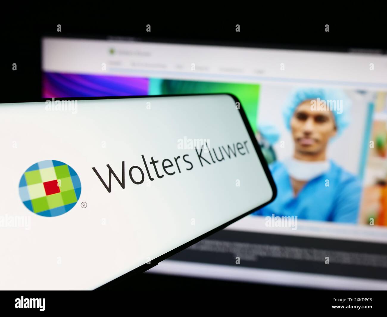 Telefono cellulare con logo della società olandese di servizi informativi Wolters Kluwer NV davanti al sito web. Mettere a fuoco la parte centrale sinistra del display del telefono. Foto Stock