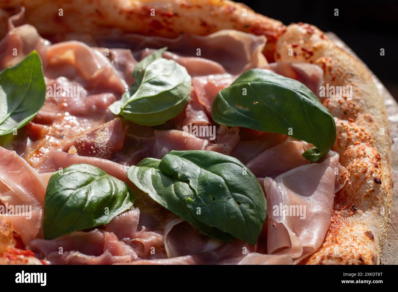 Pizza italiana con basilico e prosciutto. Foto Stock