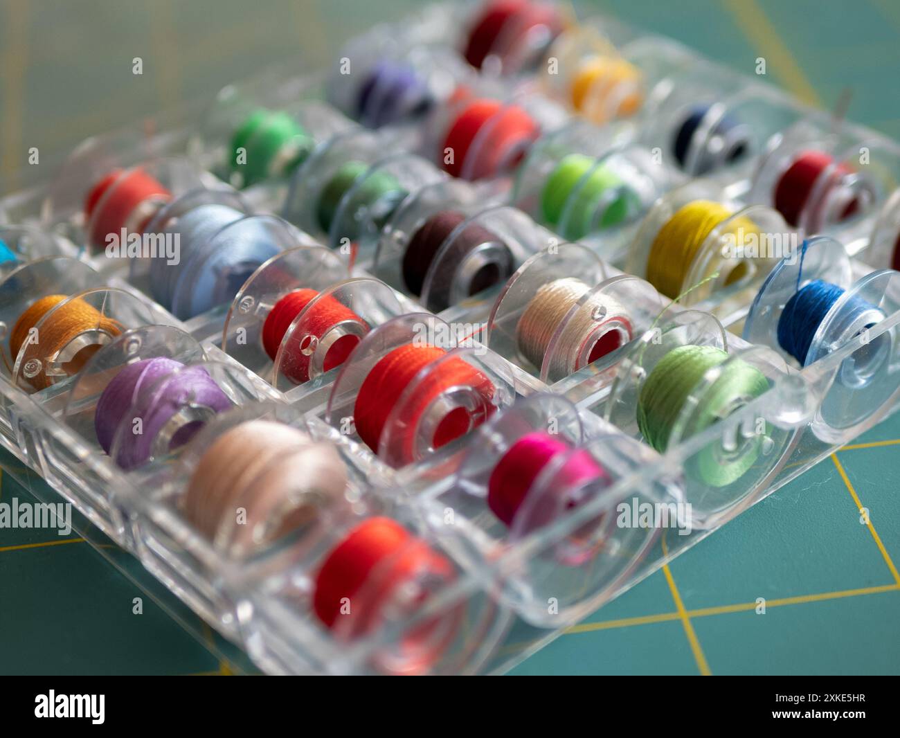Bobine con fili colorati nella scatola di plastica per lo stoccaggio, messa a fuoco selettiva. Concetto di accessori per cucire Foto Stock