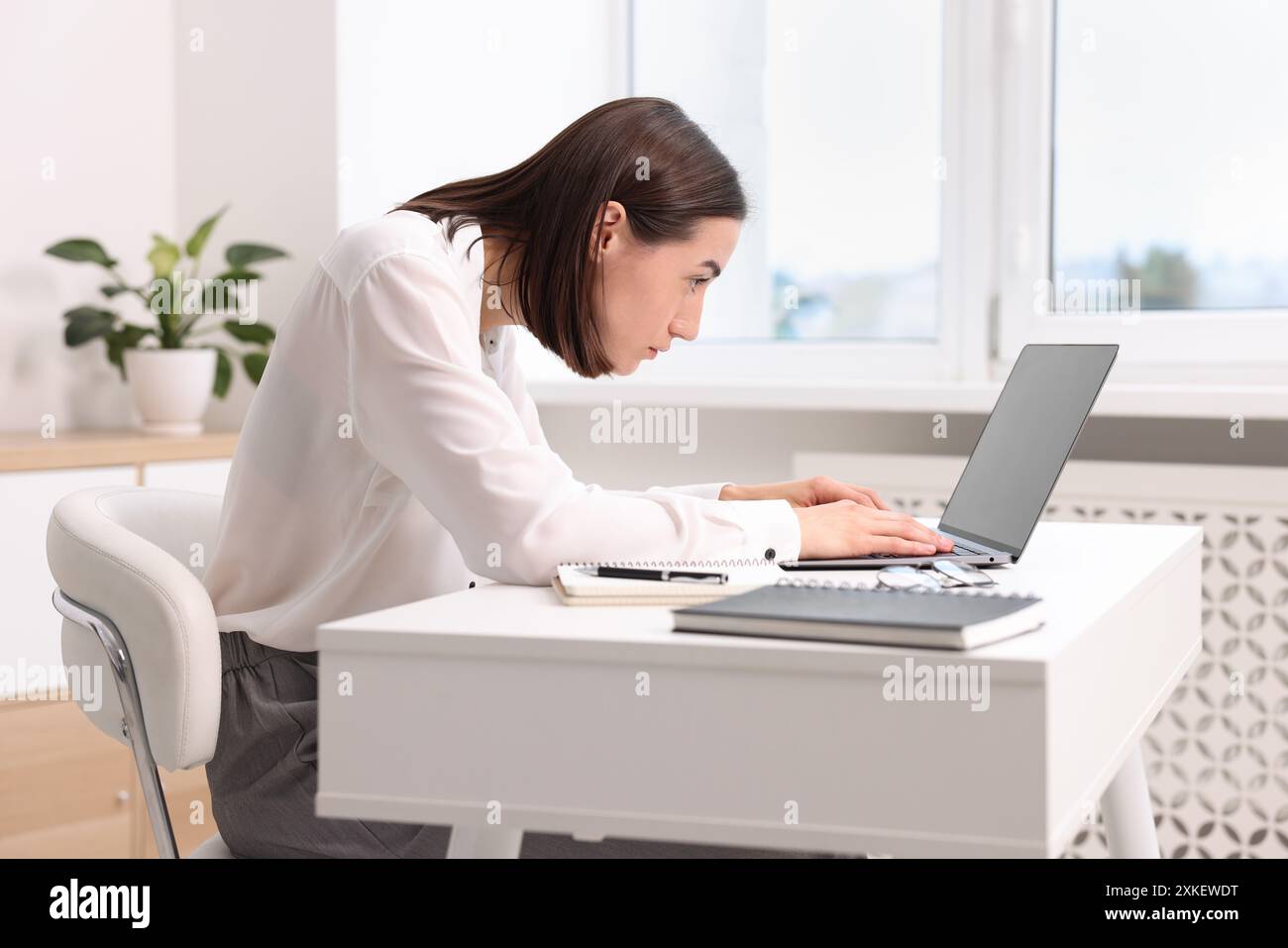 Donna con postura scarsa che lavora in ufficio Foto Stock