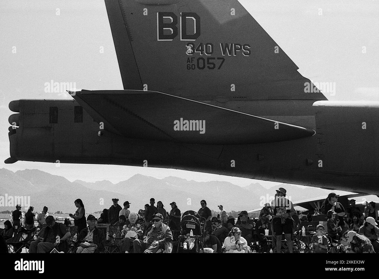 I membri della folla assistono a una dimostrazione aerea dall'ombra creata dalla coda di un bombardiere B-52 in esposizione statica durante l'Arctic Thunder Open House presso Joint base Elmendorf-Richardson, Alaska, 20 luglio 2024. Vari artisti aerei e terrestri, tra cui lo U.S. Air Force Air Demonstration Squadron "Thunderbirds" e lo U.S. Army Parachute Team, i Golden Knights, eseguono due giorni interi di acrobazie aeree di livello mondiale e dimostrazioni militari all'ATOH, un evento biennale che JBER ospita per restituire alla comunità. (Foto U.S. Air Force di Justin Connaher) Foto Stock