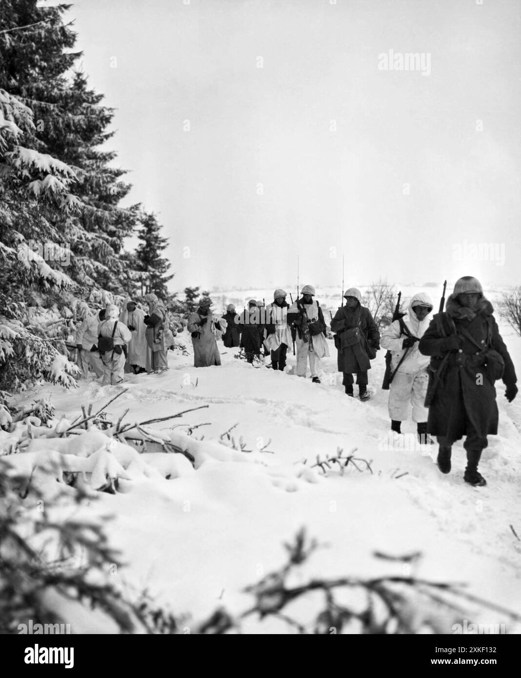 Iveldingen, Belgio 20 gennaio 1945 fanteria americana del 517th A/B Regiment, 7th Armored Division, Headquarters Co, 2nd Battalion, US First Army, cammina attraverso la neve mentre marciano lungo il bordo di un bosco, vicino a Iveldingen, nel viaggio per riconquistare St. Vith. Foto Stock