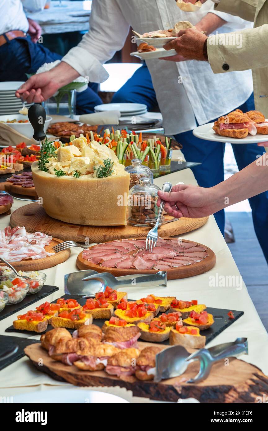Durante un evento con catering, le persone si servono da una tavola piena di salumi italiani, formaggi e altri piatti deliziosi Foto Stock