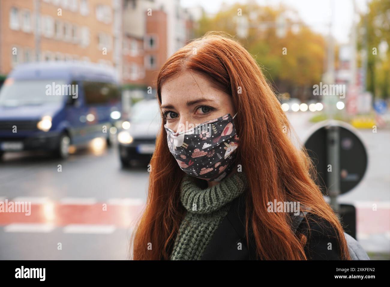 giovane donna che indossa quotidianamente tessuto maschera viso all'aperto in città raffic Foto Stock