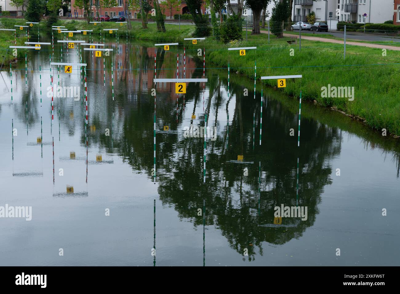 Un fiume tranquillo con boe numerate che segnano un percorso di slalom in canoa. I riflessi degli alberi e degli edifici vicini sono visibili nell'acqua. Vista dall'alto. Foto Stock