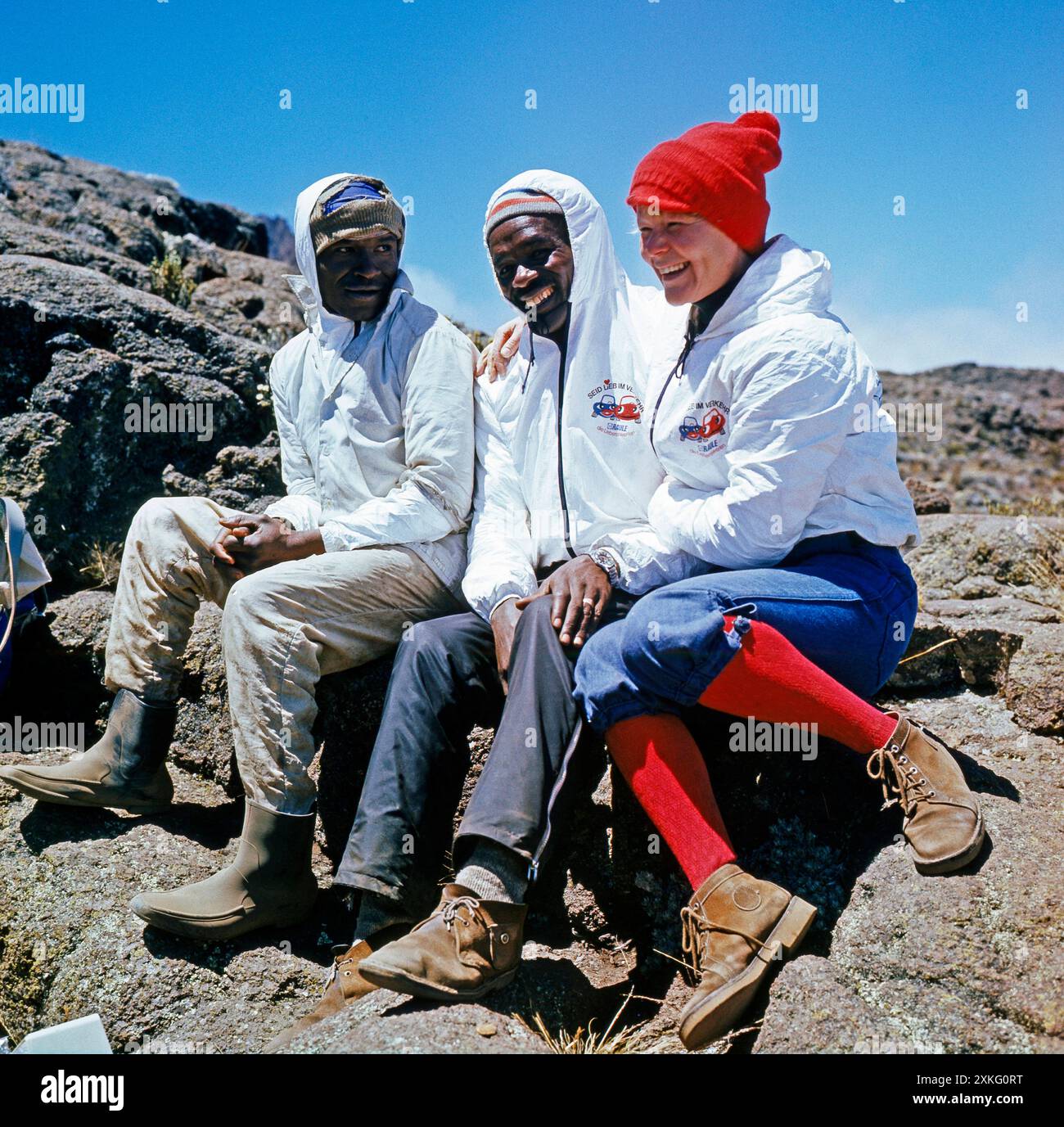 Afrikanischer Bergfuehrer und ein Hochtraeger aus dem Volksstamm der Wachagga, unterwegs auf der Marangu-Route hinauf zur Kibo-Huette, rasten in der Alpinsavanne des Kilimandscharo Kibo-Aufstieg *** Guida alpina africana e highlander della tribù Wachagga, sulla via Marangu fino al Kibo hut, riposa nella savana alpina del Kilimanjaro Kibo Foto Stock