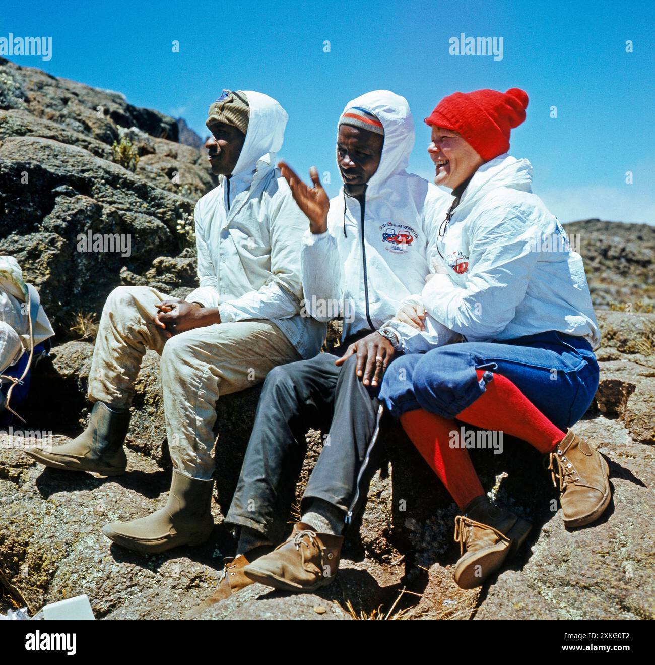 Afrikanischer Bergfuehrer und ein Hochtraeger aus dem Volksstamm der Wachagga, unterwegs auf der Marangu-Route hinauf zur Kibo-Huette, rasten in der Alpinsavanne des Kilimandscharo Kibo-Aufstieg *** Guida alpina africana e highlander della tribù Wachagga, sulla via Marangu fino al Kibo hut, riposa nella savana alpina del Kilimanjaro Kibo Foto Stock