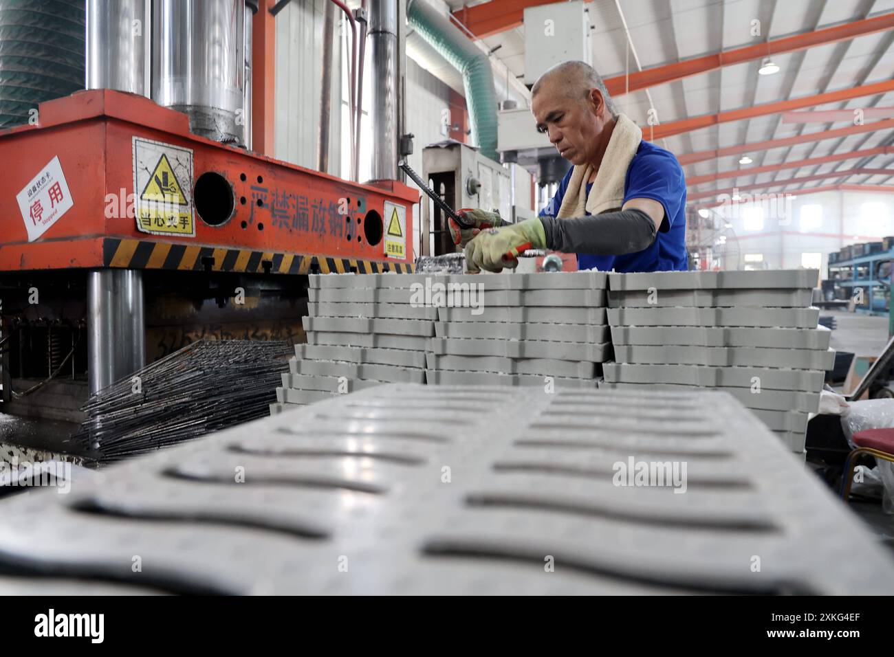 BINZHOU, CINA - 23 LUGLIO 2024 - Un lavoratore utilizza il fango rosso per lavorare materiali compositi polimerici in un'officina di un produttore di materiali compositi Foto Stock