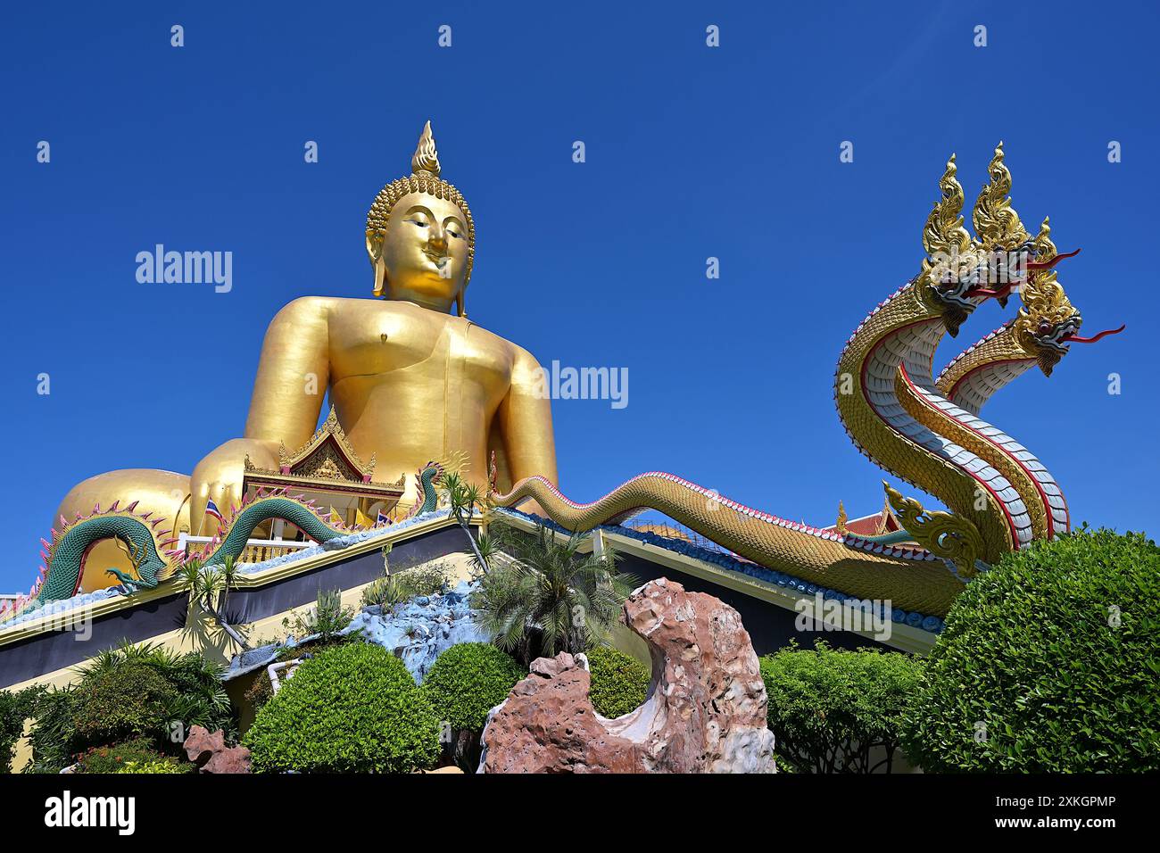 Vista della gigantesca immagine di Phra Buddha Maha Nawamin al Wat Muang nella provincia di Ang Thong dalla sua base, fiancheggiata da sculture protettive di Naga Foto Stock