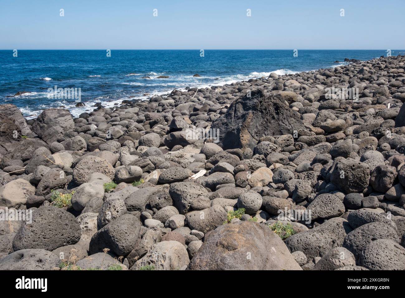 Enormi massi di antiche rocce vulcaniche coprono il litorale della riserva naturale di la Timpa di Acireale, vicino a Catania, Sicilia, Italia Foto Stock