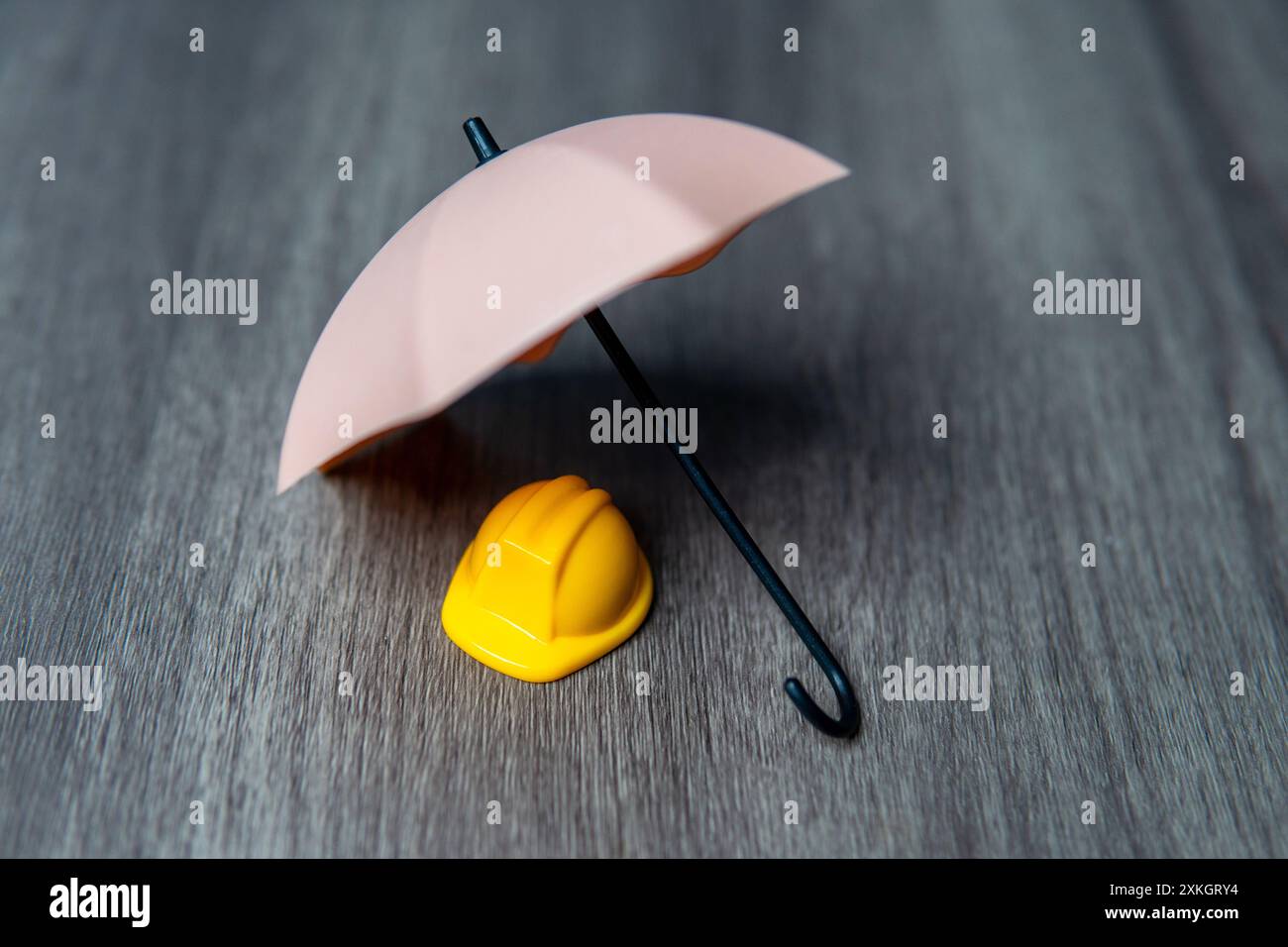 Un elmetto giallo e un ombrello. Assicurazione per i lavoratori, concetto di sicurezza prima di tutto. Foto Stock