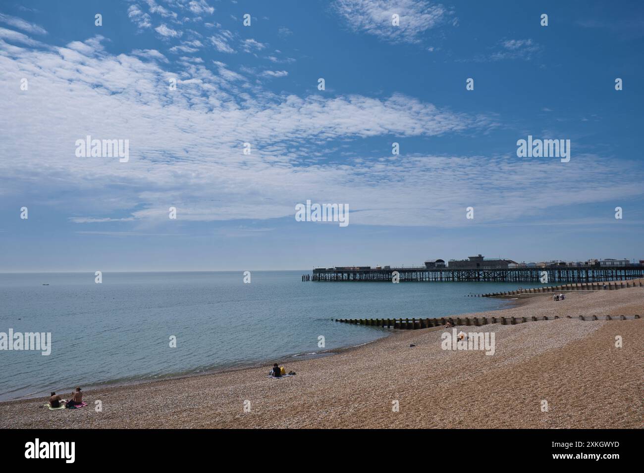 La gente del posto si gode un pomeriggio al sole estivo a hastings Beach, nell'East Sussex Foto Stock