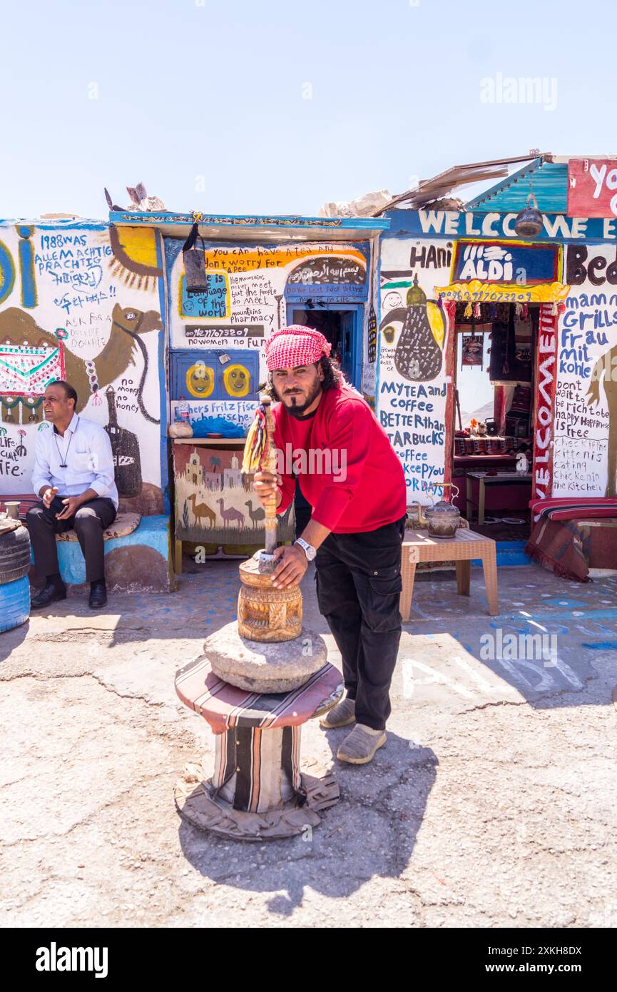 Il proprietario macina il caffè in un macinacaffè tradizionale presso la caffetteria Aldi Bedouin e un chiosco di souvenir presso il Moujib Panorama vicino a Wadi Mujib, in Giordania Foto Stock