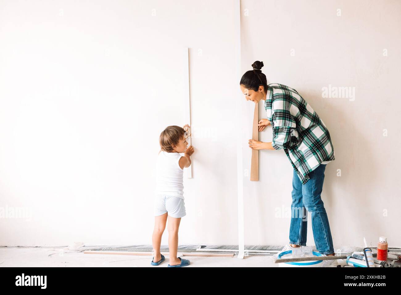 Il bambino e la madre sorridente scelgono le decorazioni per i futuri interni della stanza. La giovane donna gioca con suo figlio durante la ristrutturazione. Mamma e bambino A. Foto Stock