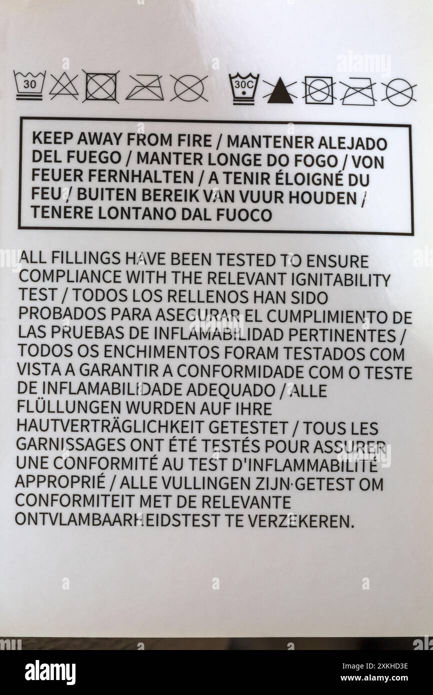 Tenere lontano dal fuoco, tutti i riempimenti sono stati testati per garantire la conformità al relativo test di infiammabilità - dettaglio riportato sull'etichetta in molte lingue Foto Stock