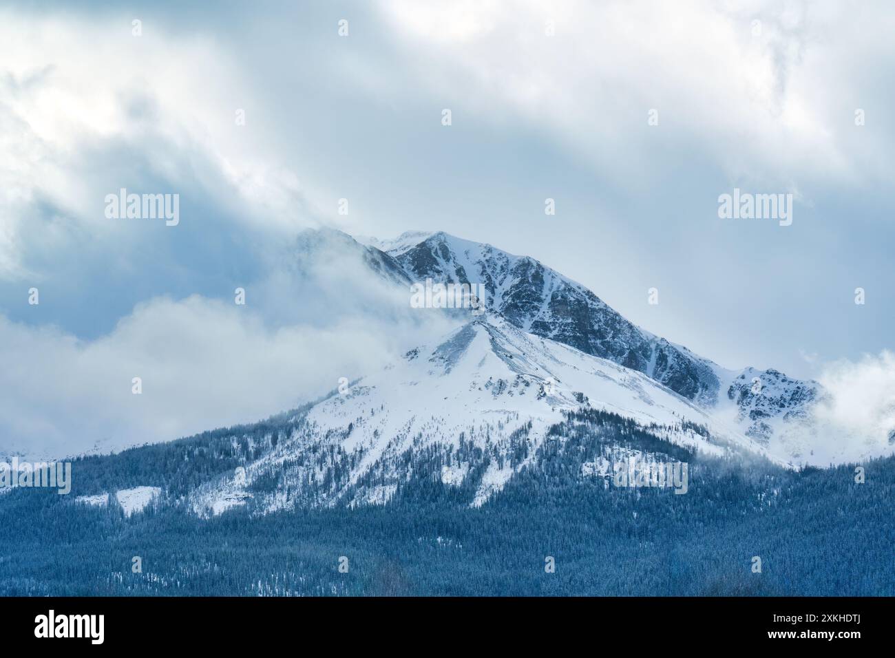 Maestose montagne rocciose innevate con nuvole che scorrono nella natura selvaggia della campagna Foto Stock