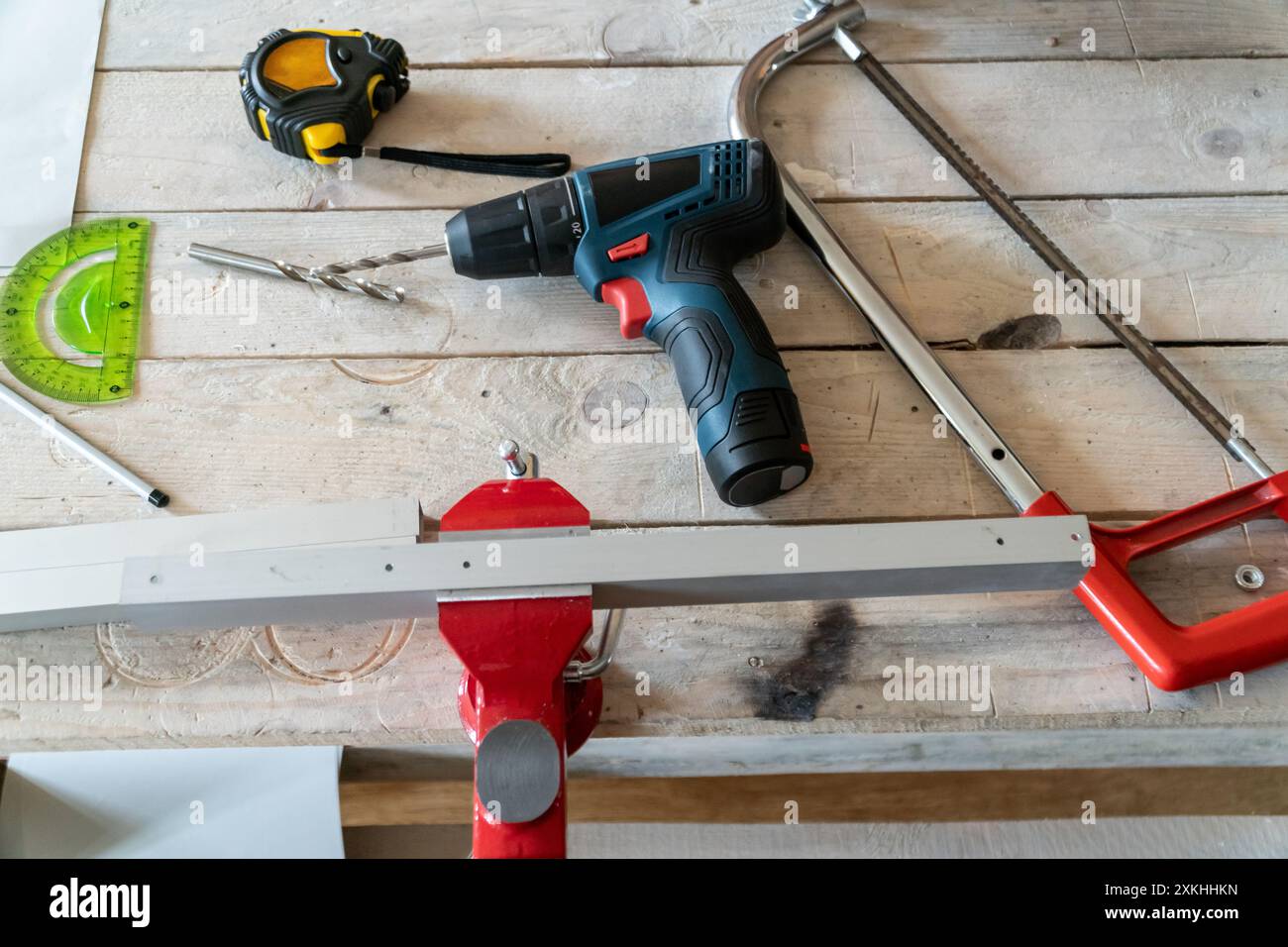 Area di lavoro per la riparazione di abitazioni con trapano elettrico, sega per metallo e morsa per fabbro con dettaglio chiuso a chiave. Foto Stock