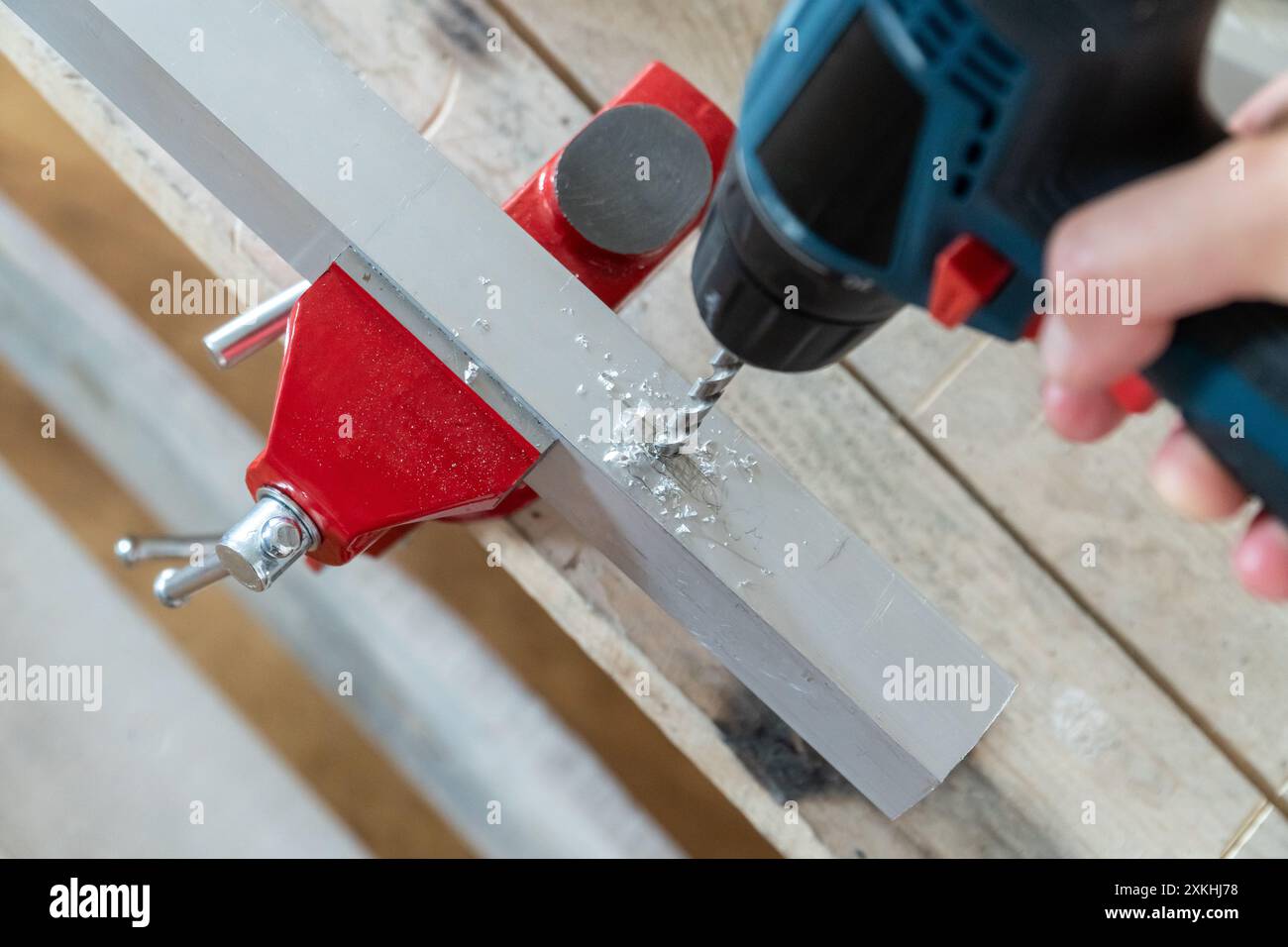 Mano maschio con un cacciavite elettrico utilizzato come trapano fori nei dettagli in alluminio. Concetto di riparazione della casa Foto Stock