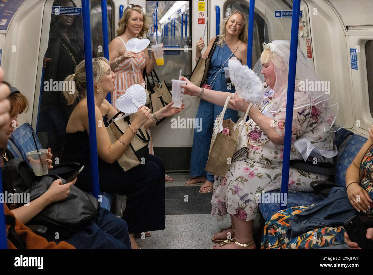 Le addette alle feste viaggiano insieme sulla rete metropolitana di Londra in un caldo weekend estivo intenso, Londra, Inghilterra, Regno Unito Foto Stock