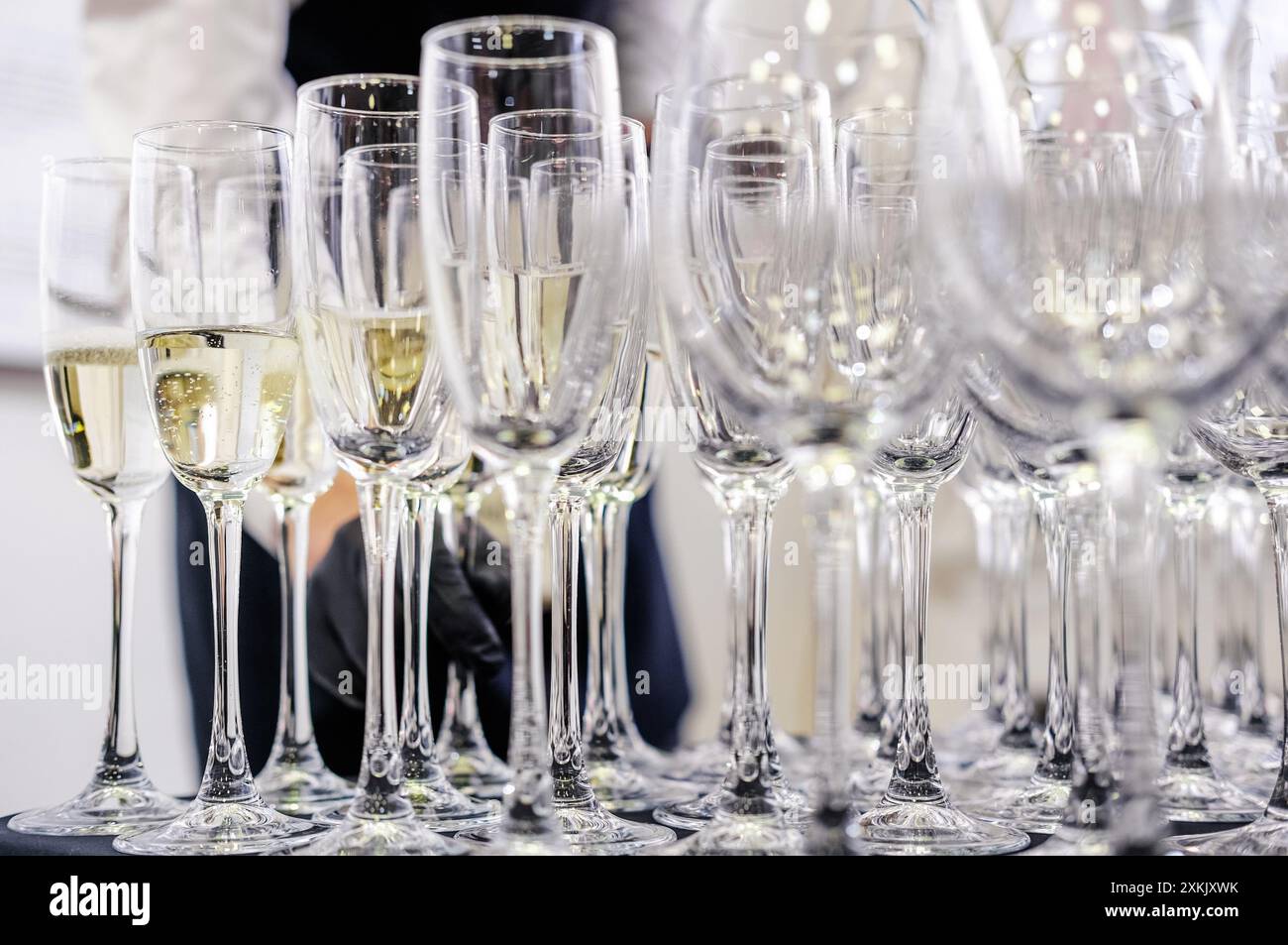 Bicchieri multipli di champagne ordinati, pronti per essere serviti in un evento formale. Ripresa orizzontale. Foto Stock