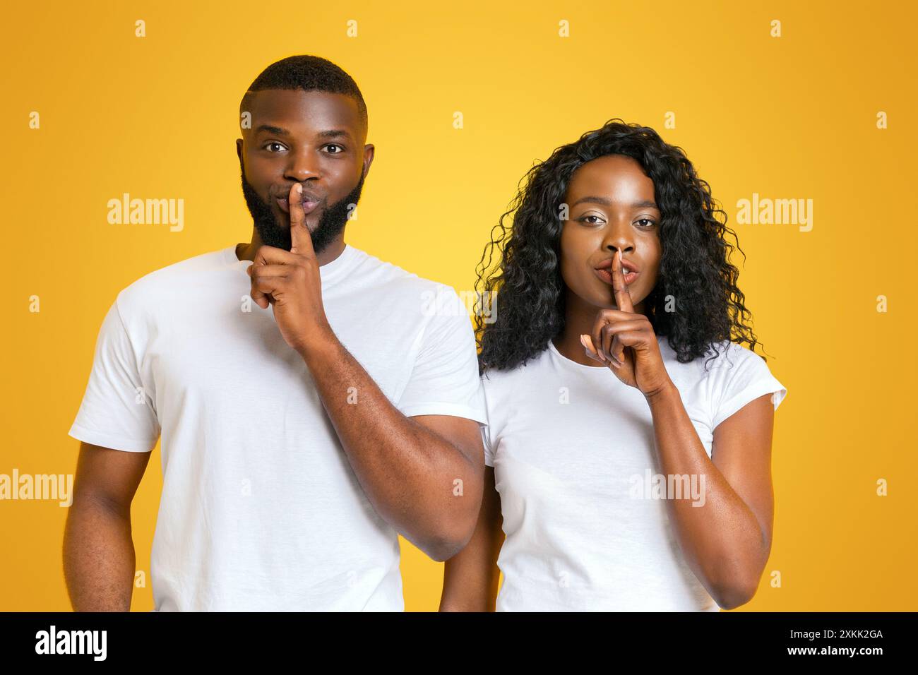 Uomo e donna Shushing su sfondo giallo Foto Stock