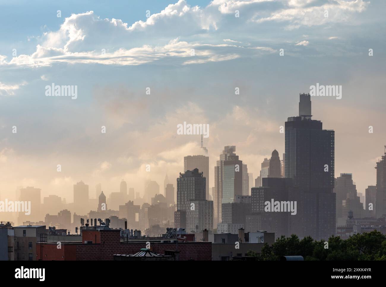 Lower Manhattan e le nuvole sono illuminate dal sole pomeridiano visto da un tetto a Prospect Heights, Brooklyn, New York, Stati Uniti. Foto Stock