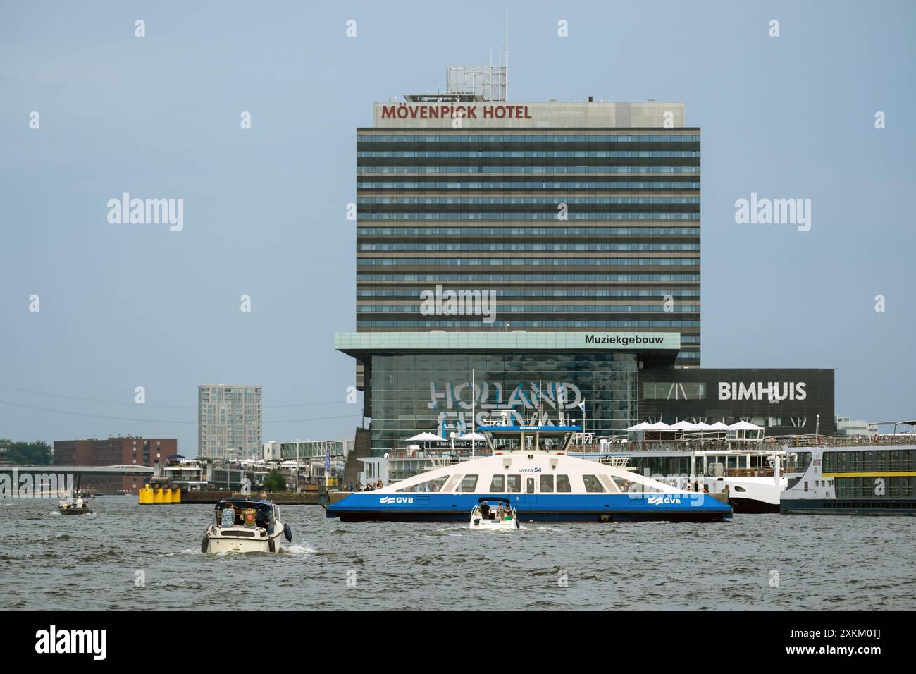 18.06.2023, Paesi Bassi, Olanda settentrionale, Amsterdam - Moevenpick Hotel Amsterdam City Centre sull'Amstel con traghetto e barche. 00A230618D210CAROEX.JPG Foto Stock