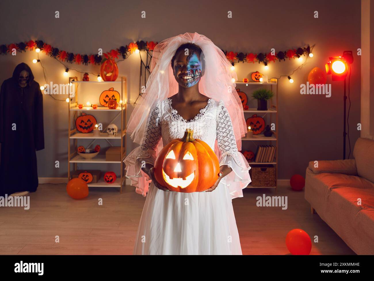 Ritratto di una giovane donna dalla pelle scura sorridente vestita da sposa morta alla festa di Halloween. Foto Stock