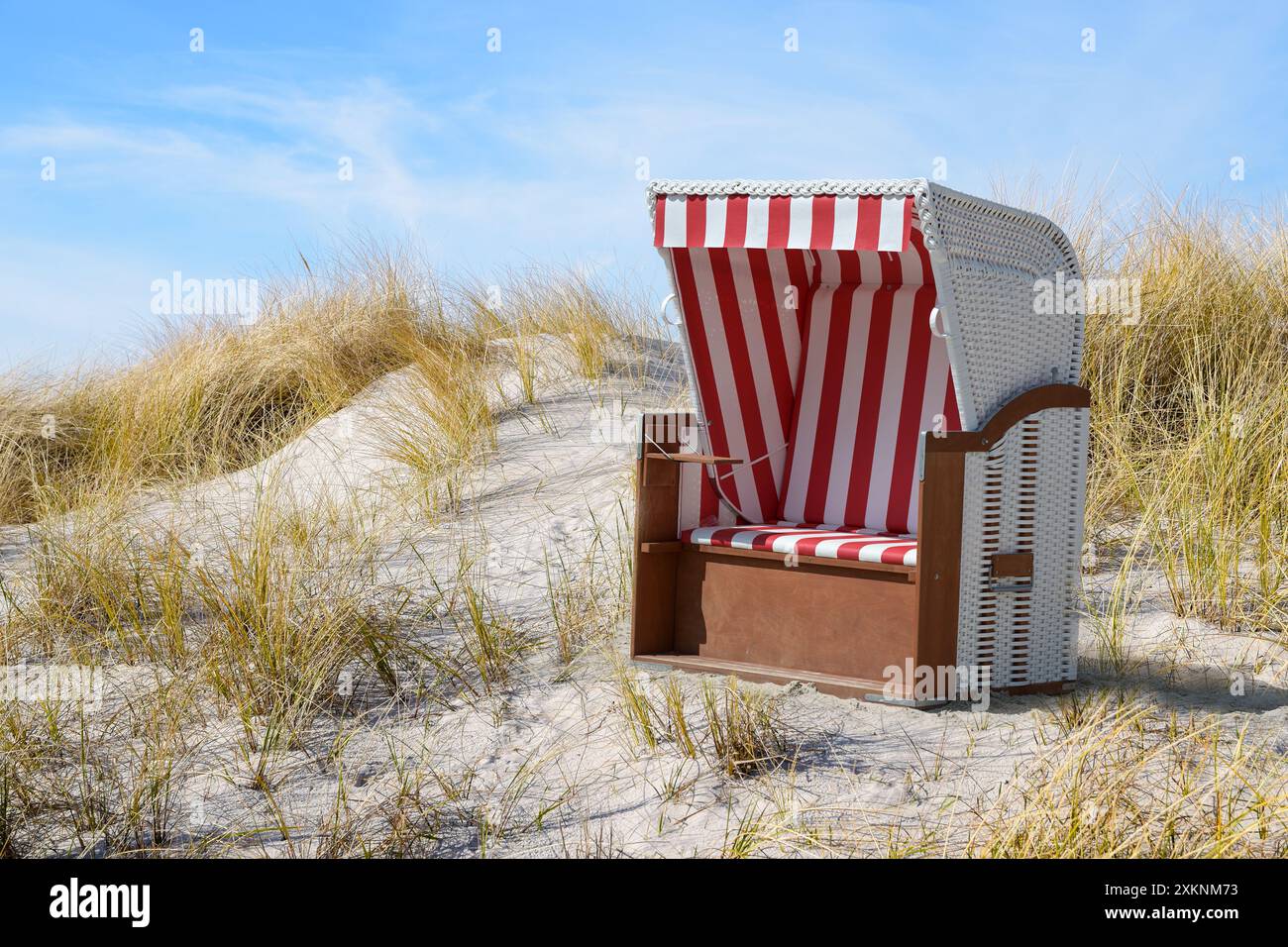 Sdraio in vimini a righe rosse e bianche tra le dune di sabbia tra l'erba secca di marram del Mar Baltico e un cielo blu, felice vacanza estiva saluto ca Foto Stock