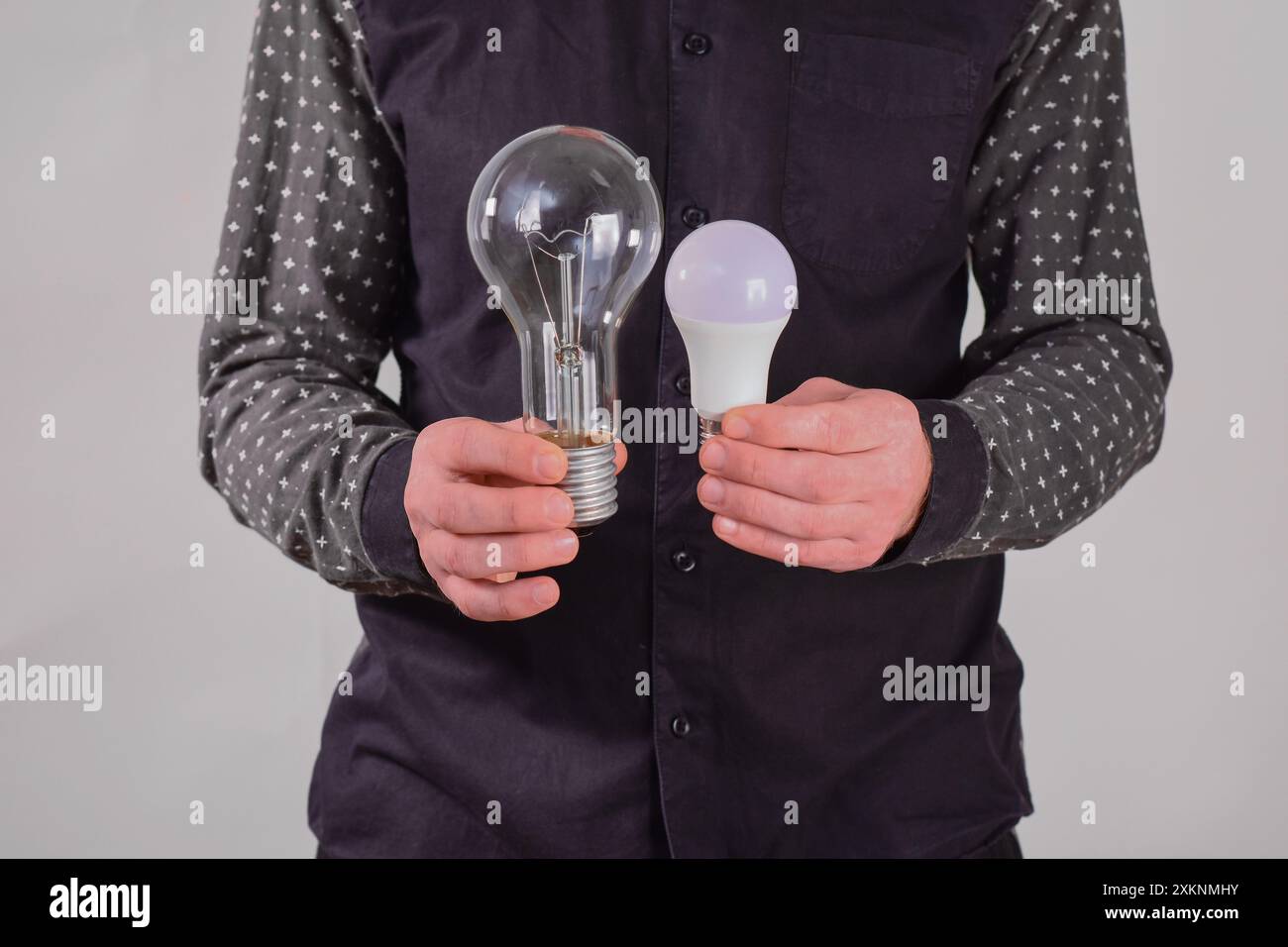 il concetto di efficienza energetica. Lampada a LED e lampada a incandescenza in mano Foto Stock