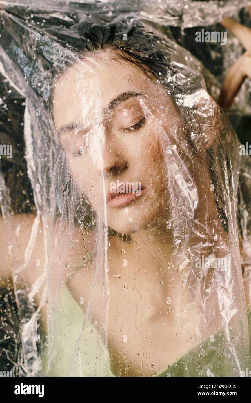 Un volto femminile in parte nascosto, evocando un'atmosfera da sogno, con la plastica addosso a lei. Foto Stock