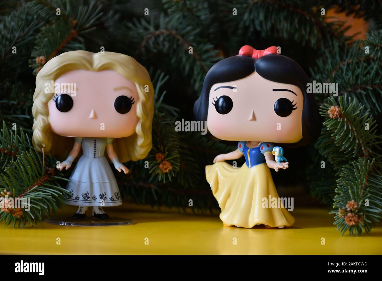 Funko Pop action figure di Alice nel Paese delle meraviglie e della principessa Disney Biancaneve. Rami di abete, atmosfera natalizia, pavimento giallo, favoloso, magico. Foto Stock