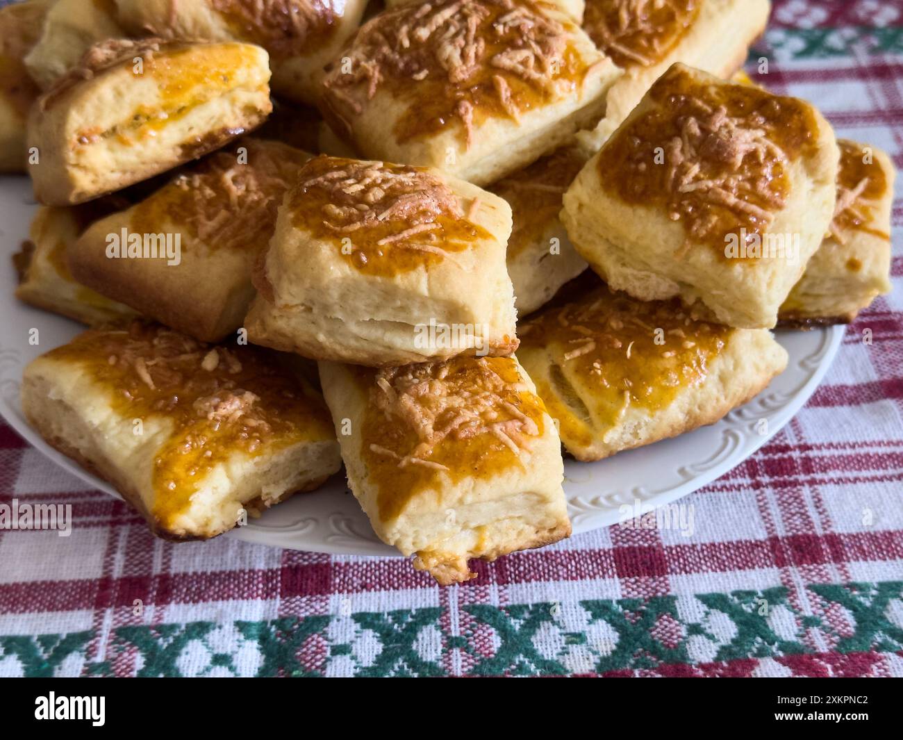 Primo piano di un piatto ripieno di focaccine al formaggio appena sfornate poste su una tovaglia colorata a scacchi. Foto Stock