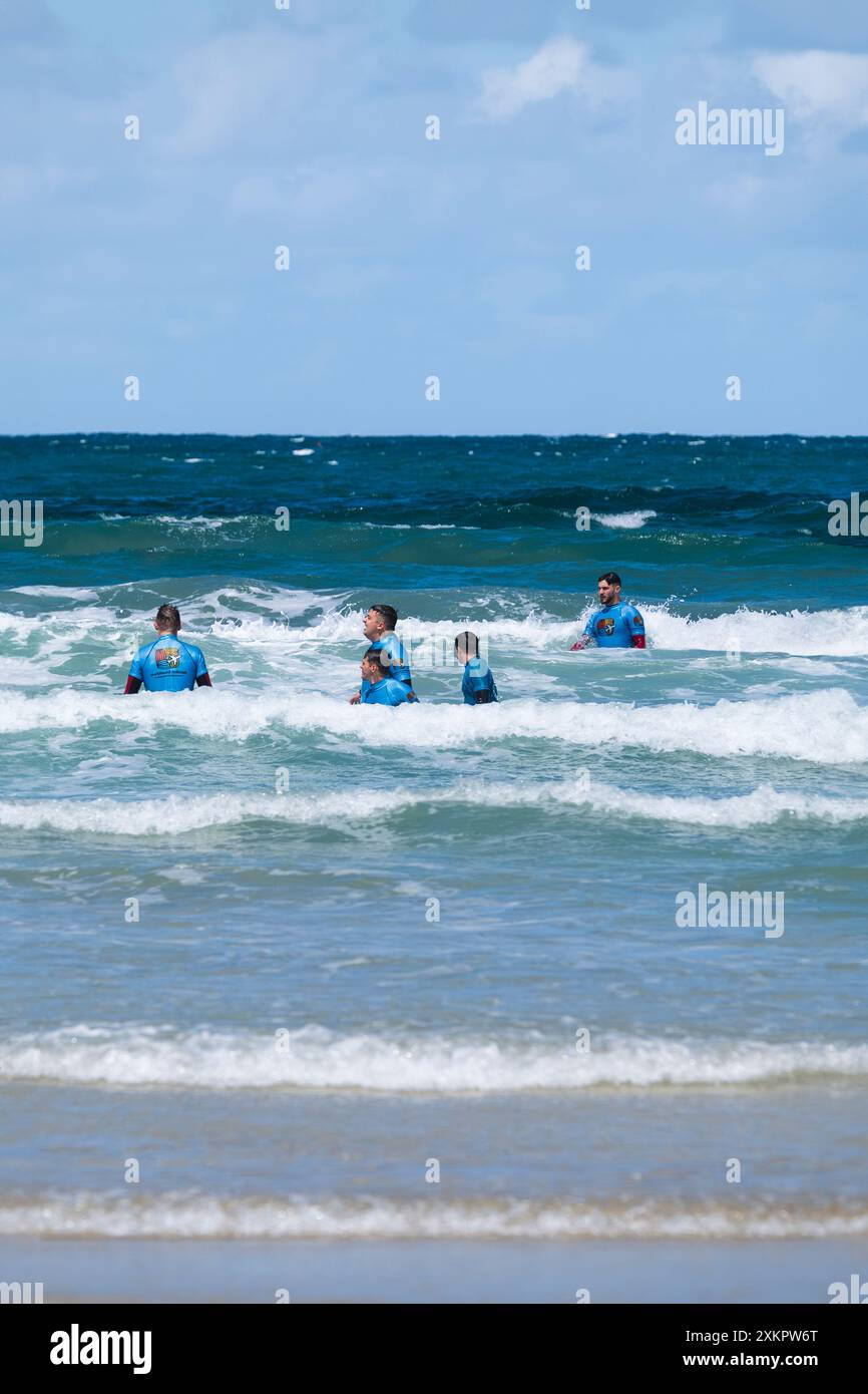 Un gruppo di vacanzieri che tengono una lezione di surf alla spiaggia di Towan a Newquay, in Cornovaglia, nel Regno Unito. Foto Stock