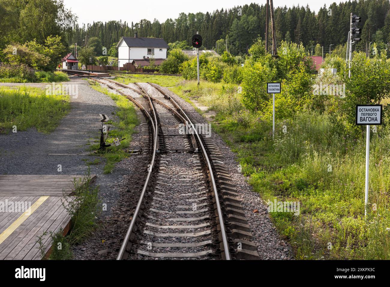 Un binario ferroviario vuoto che gira a sinistra con un commutatore ferroviario, i segnali stradali bianchi hanno il testo russo, che significa: Locomotive Stop, First Car Stop Foto Stock