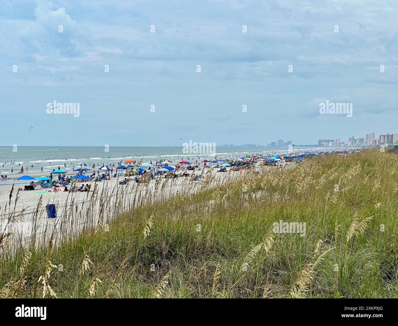 I vacanzieri affollano le coste sabbiose, mentre una dispersione di condomini e case segna l'orizzonte oltre le dune di North Myrtle Beach. Foto Stock