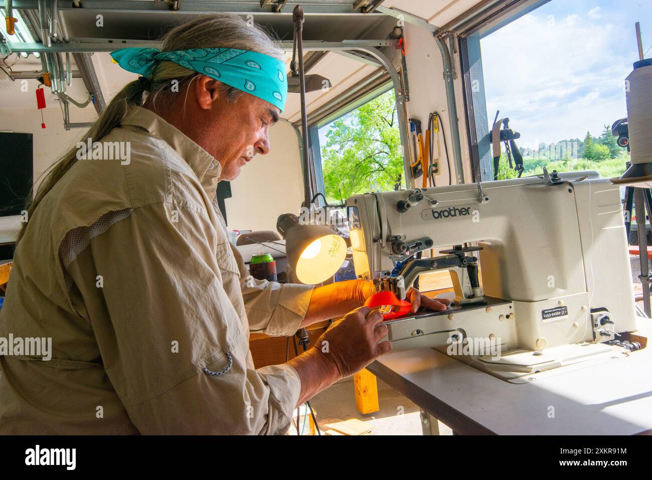 Un maschio adulto che utilizza una macchina da cucire industriale per cucire tessuti pesanti. Durango, Colorado Foto Stock