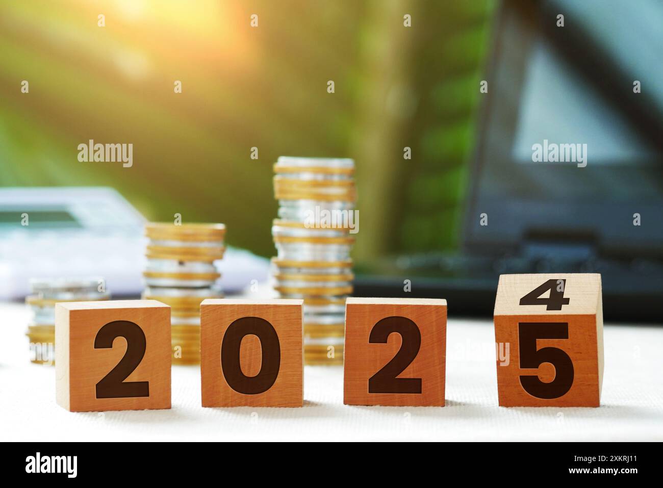 Blocchi di legno di cambiamento e conto alla rovescia con incisioni anni dal 2024 al 2025 con calcolatrice, monete e foglie di sfondo bokeh naturale Foto Stock