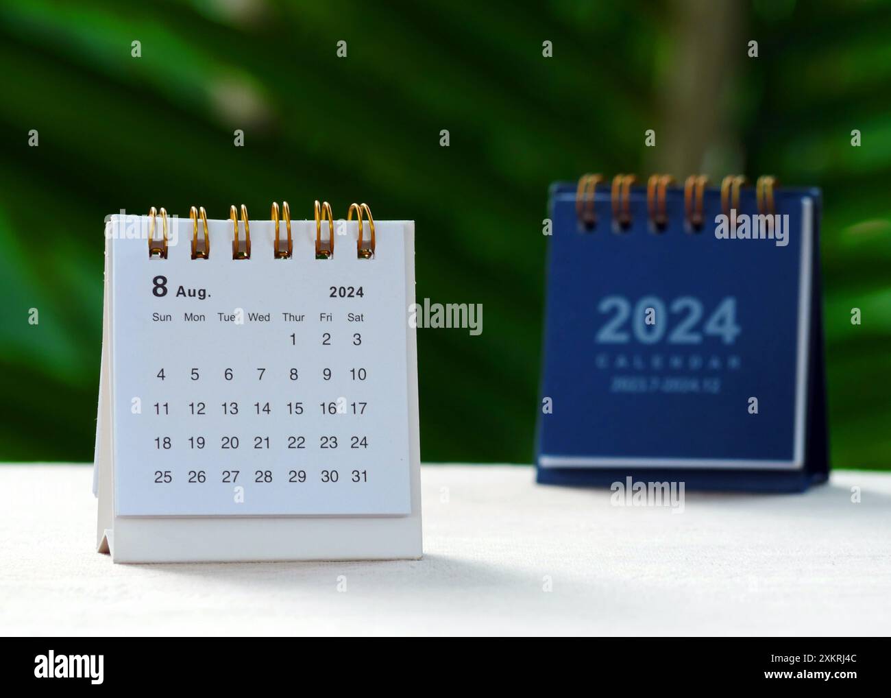 Due scrivanie per agosto 2024 su tavolo in legno con sfondo bokeh Foto Stock