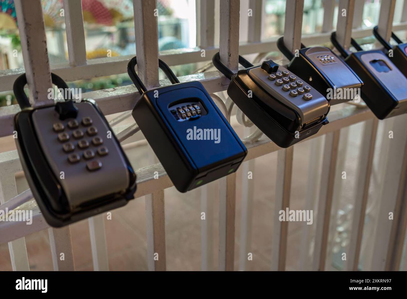 Cassette di sicurezza con chiave combinata montate su ringhiera bianca, primo piano Foto Stock