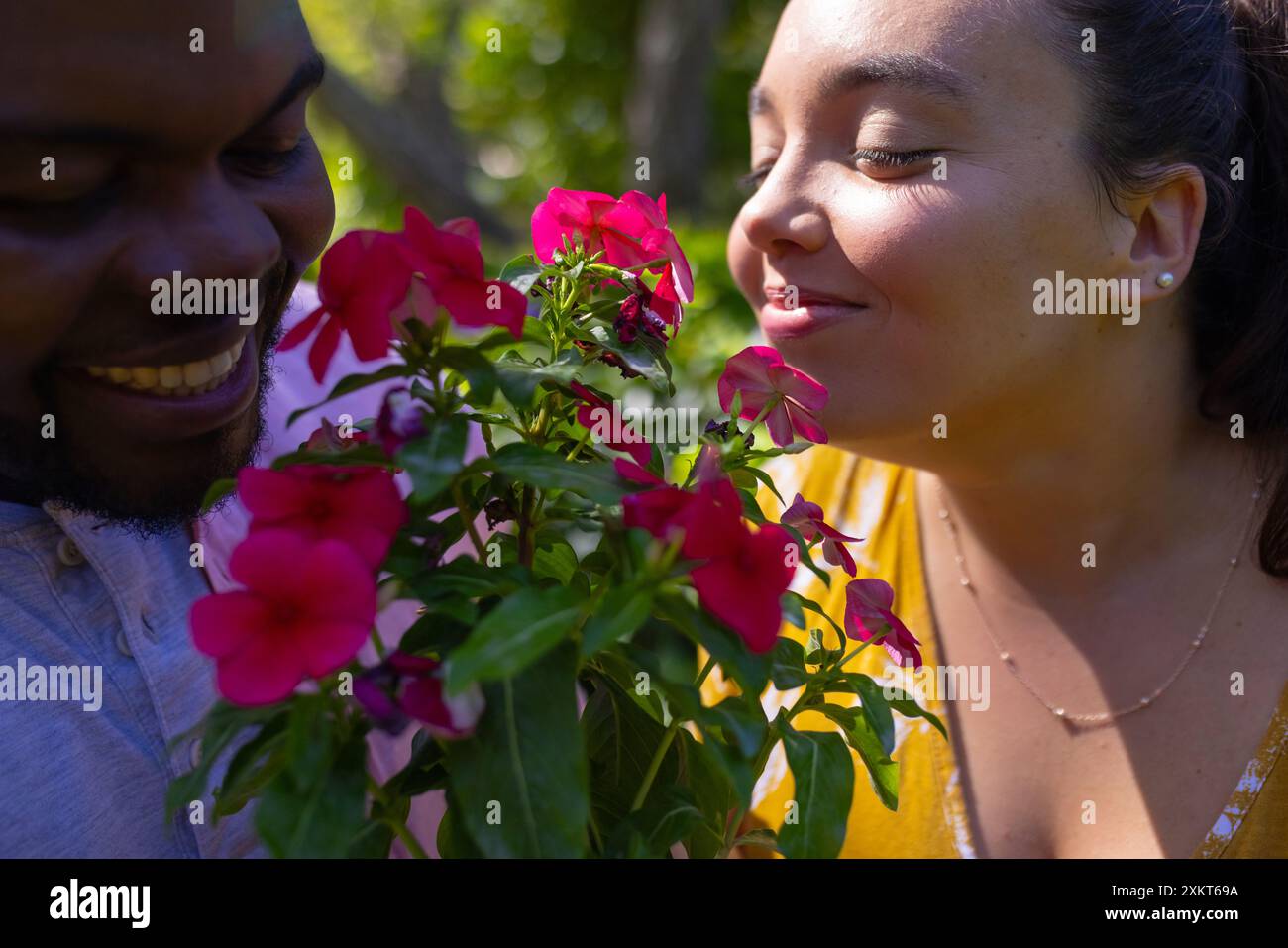 Goditi i fiori vivaci insieme nel giardino soleggiato, sorridendo gli amici che si divertono Foto Stock