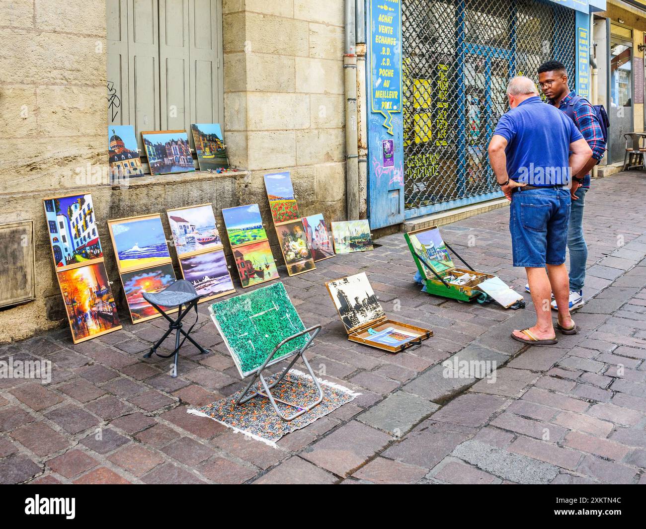 Artista dilettante con opere d'arte disposte sul marciapiede che discutono l'arte con persone in strada - Tours, Indre-et-Loire (37), Francia. Foto Stock