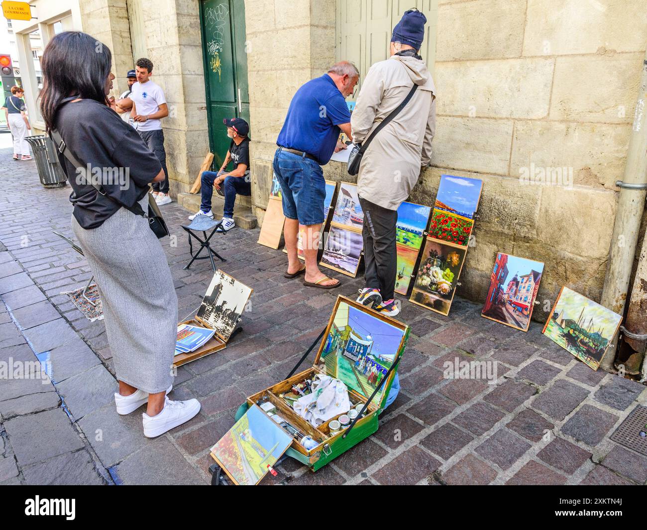 Artista dilettante con opere d'arte disposte sul marciapiede che discutono l'arte con persone in strada - Tours, Indre-et-Loire (37), Francia. Foto Stock