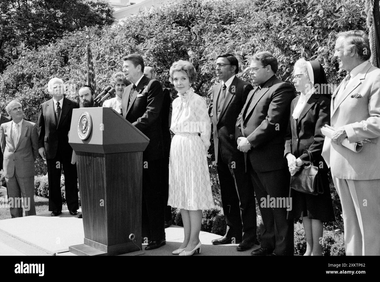 Il presidente degli Stati Uniti Ronald Reagan in piedi al leggio con la First Lady Nancy Reagan e altri durante la cerimonia della giornata nazionale di preghiera, Casa Bianca, Washington, D.C., USA, Chick Harrity, U.S. News & World Report Magazine Photography Collection, 6 maggio 1982 Foto Stock