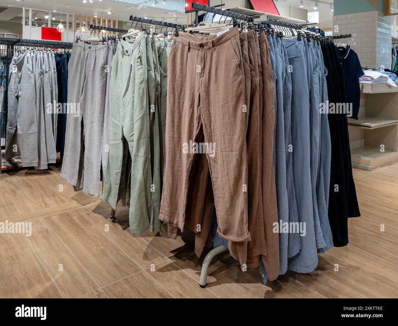 Italia - 25 luglio 2024: Pantaloni di lino estivi di vari colori esposti su clothesline in vendita nel negozio di abbigliamento Foto Stock
