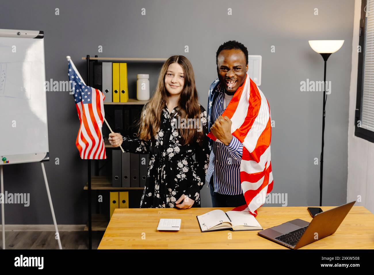 Un uomo sorridente ang girl che tiene in mano la bandiera degli Stati Uniti in ufficio. Foto Stock